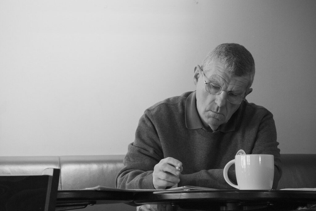 Elderly man fills out surveys while drinking coffee