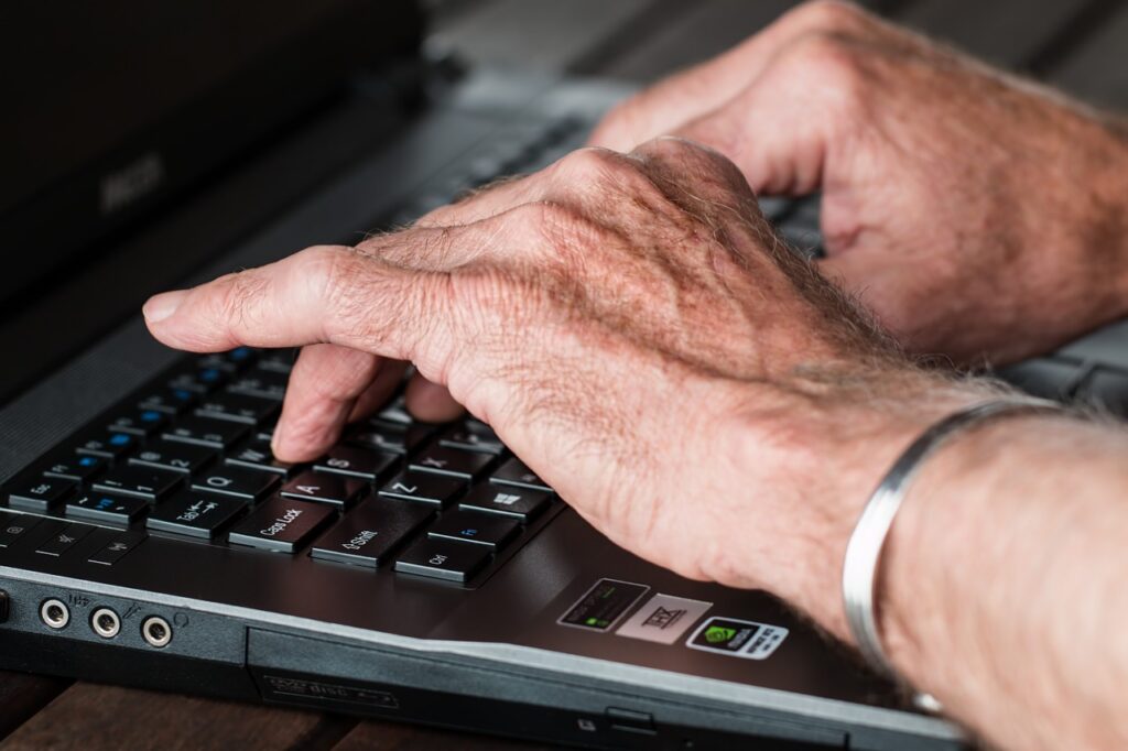 elderly hands typing; Social Security beneficiaries targeted by scammers