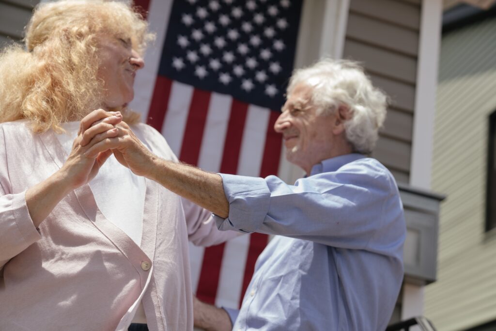 Elderly LGBTQ couple dancing in front of American flag