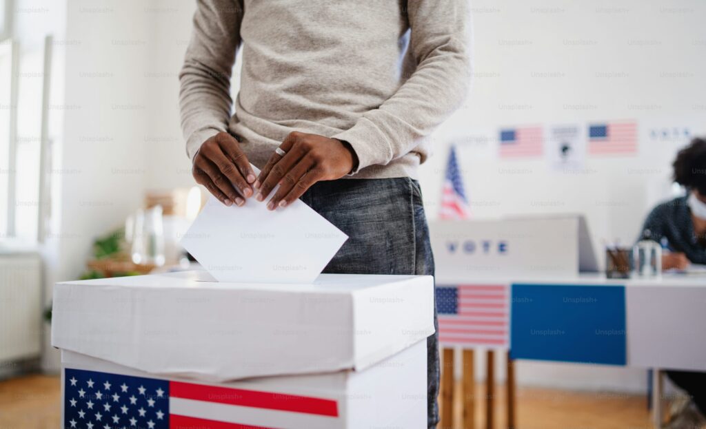 Unrecognizable african-american man putting his vote in the ballot box, usa elections and coronavirus concept.